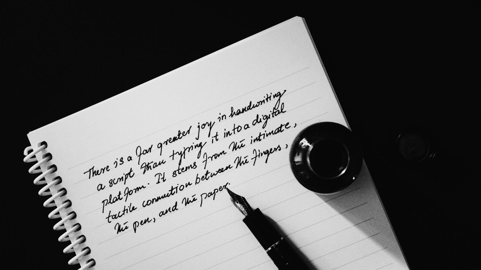 storytelling-scrittura-sceneggiatura Inquadratura dall'alto di un quaderno con scrittura a mano, penna stilografica e boccetta d'inchiostro