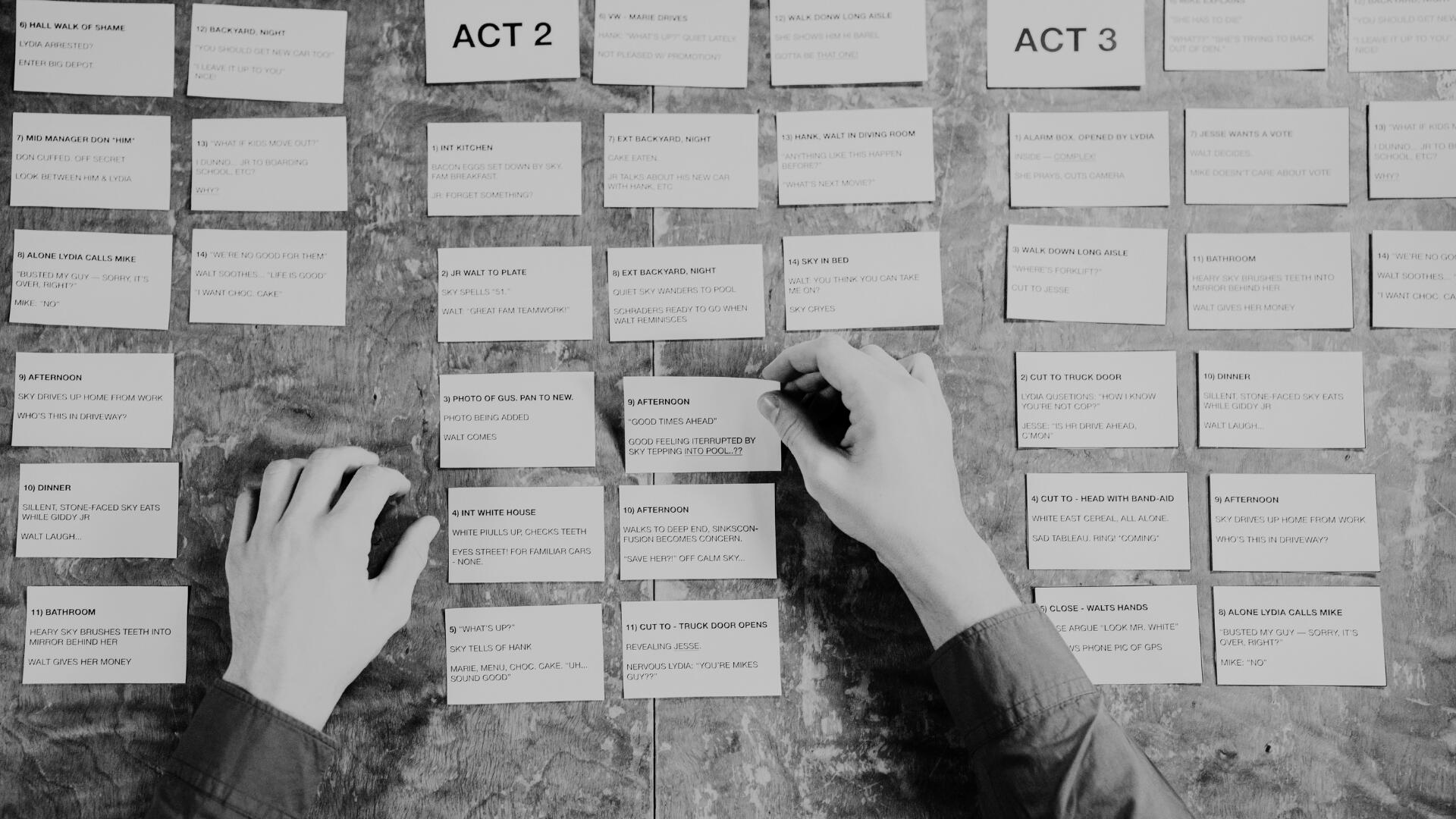 Revisione della Sceneggiatura e Struttura Narrativa — Script Review Mani che organizzano ed esaminano schede di pianificazione narrativa divise in atti su un tavolo di lavoro.
